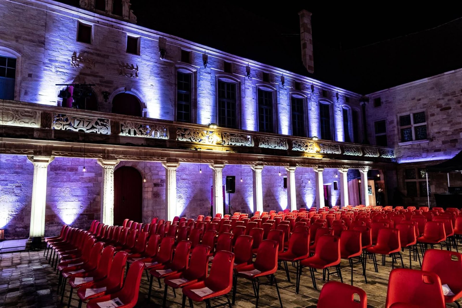 Page d'accueil Photo de Gilles de trèves la nuit avec chaises rouges et une ampoule led en avant plan