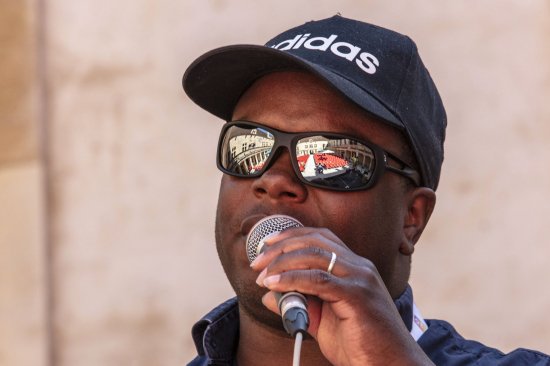 Photo en gros plan de Hervé Fontaine, micro à la main et chaussé de lunettes miroir, lors du festival Bar'EnVoix 2023