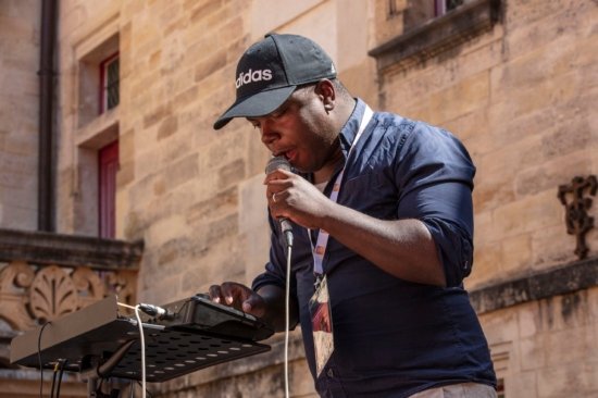 Photo de Hervé Fontaine, micro à la main et paramétrant son looper lors du festival Bar'EnVoix 2023