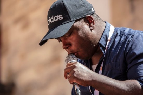 Photo en gros plan de Hervé Fontaine, micro à la main et casquette sur la tête, lors du festival Bar'EnVoix 2023