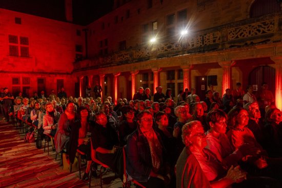 Public vu de face dans la cour Gilles de Trèves avec les coursives et les colonnades éclairées de rouge