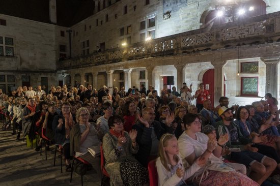 Le public applaudit dans une cour du collège éclairée de blanc