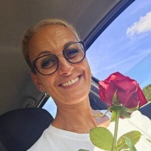 Fati EL HAOUTI, membre du bureau, avec des lunettes et une rose à la main.