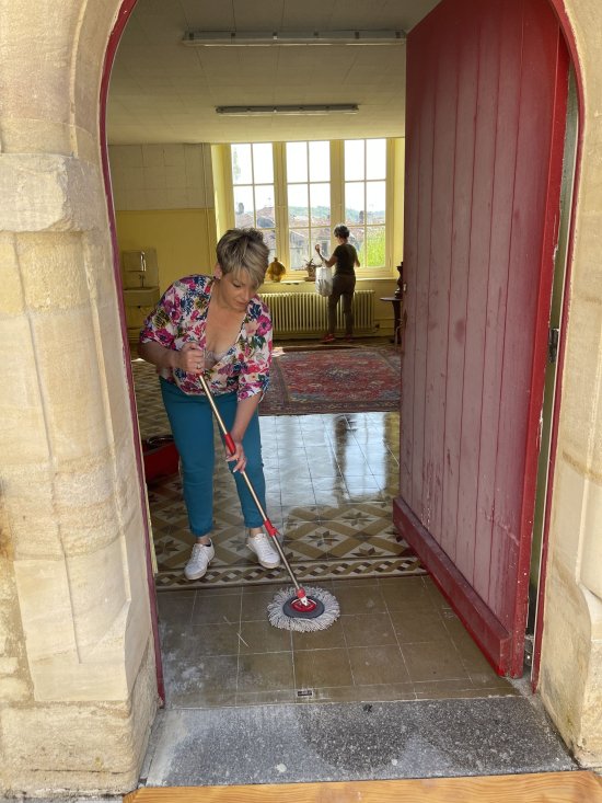 Bar'EnVoix 2023 - Photo des coulisses - Séverine passe la serpillère dans une pièce du collège.