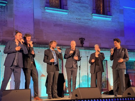 Photo des 6 artistes du groupe Slixs sur la scène du collège devant un mur éclairé de nuances de bleu et mauve.