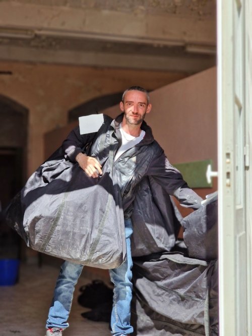 Jérémie transporte des gros sacs contenant les toiles des barnums