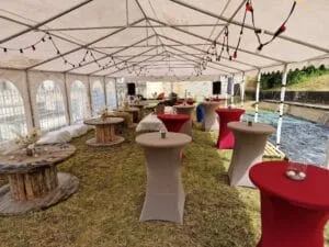 Le barnum principal de la guinguette avec des tourets et mange-debout rouges et gris décorés. Vue avant l'arrivée des festivaliers.