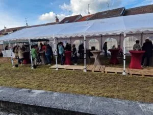 Les festivaliers à la guinguette en pleine discussion et dégustation vus en plan large depuis le chemin d'accès.