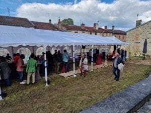 Les festivaliers à la guinguette en pleine discussion et dégustation vus en plan large depuis le chemin d'accès.