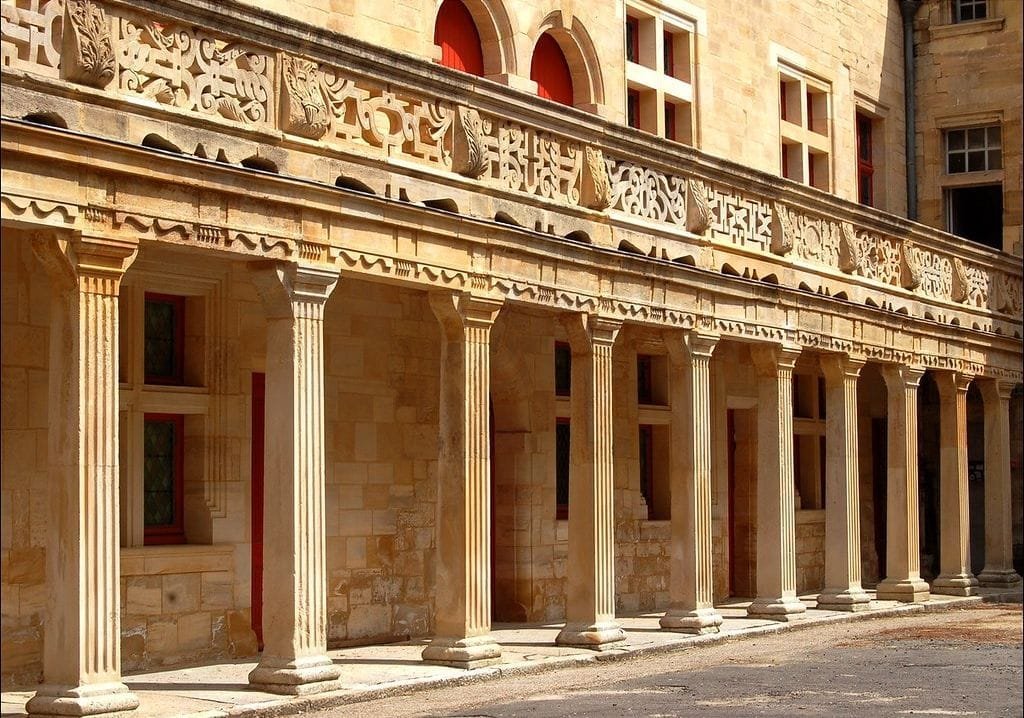 Un côté de la cour du collège Gilles du Trèves montrant la coursive sculptée portée par des colonnes de pierre.