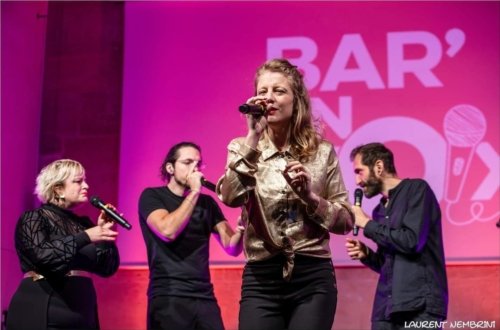 Mélody du groupe Ommm, à l'avant de la scène en train de chanter, Marion, Svent et Mathis sont à l'arrière.