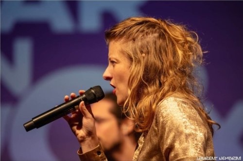 Gros plan de coté sur Mélody du groupe Ommm en train de chanter micro à la main.