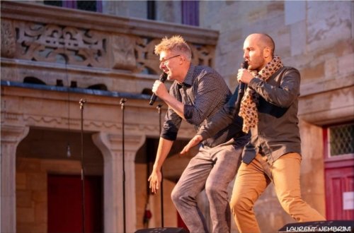 Emmanuel et Mathieu du groupe Opus Jam, micro à la main chantent en duo sur scène dans la cour du collège Gilles de Trèves dans le soleil couchant.