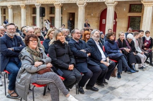Le public assis, écoute attentivement les artistes sur la scène du collège Gilles de Trèves.