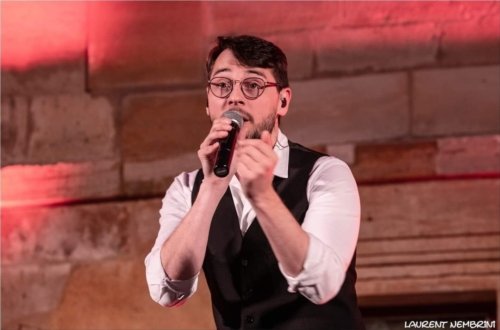 Gros plan sur Philippe du groupe Just Vox, micro à la main en train de chanter.