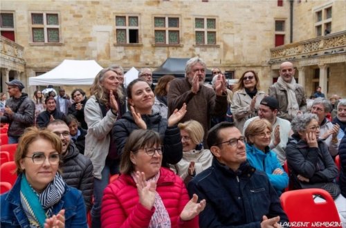 Le public, vu de face, visages souriants et debout, applaudissant dans la cour du collège Gilles de Trèves.
