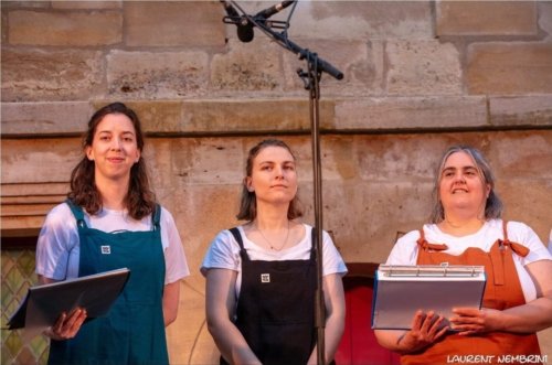 3 chanteuses de l'Atelier Chorale U derrière un micro, partitions à la main.