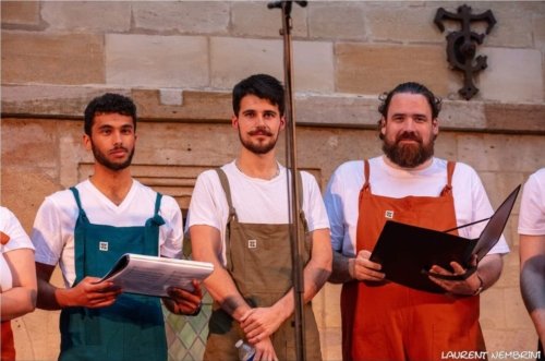 3 chanteurs de l'Atelier Chorale U derrière un micro, partitions à la main.