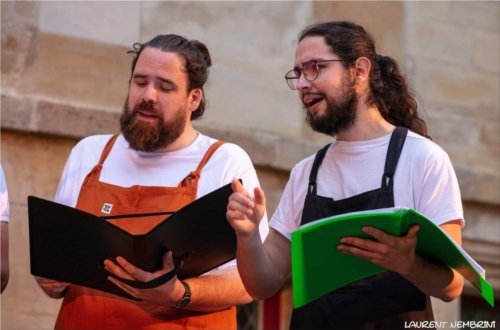 2 chanteurs de l'Atelier Chorale U en train de chanter, partitions à la main.