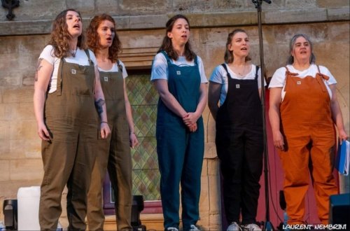 5 chanteuses de l'Atelier Chorale U en pleine action derrière un micro en salopette multicolores.