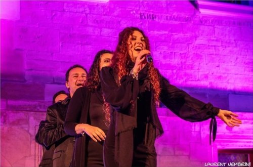 Le groupe Mezzotono, à la queue-leu-leu en train de chanter devant une paroi éclairée de violet.