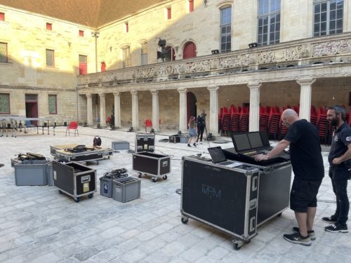 Fred et Jérémie dans la cour du collège Gilles de Trèves devant la console de la régie lumière en train de régler les paramètres.