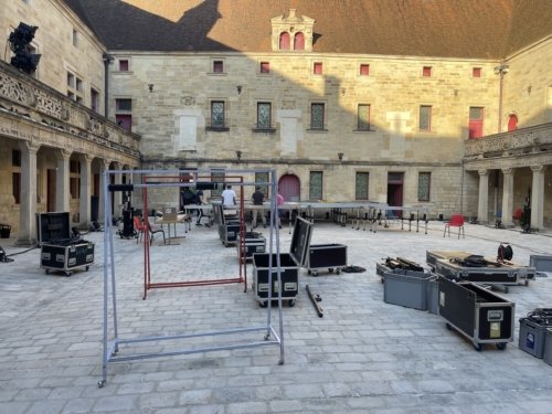 Photo d'ensemble de l'installation technique de la cour du collège Gilles de Trèves. En premier plan, les flight case, des portiques... Sous un soleil couchant