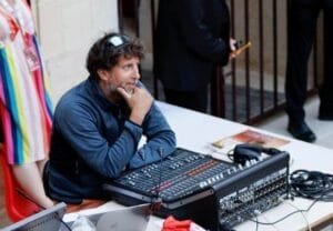 À la table, Laurent Bourquin utilise son ordinateur portable et une table de mixage pour la régie son en 2023.