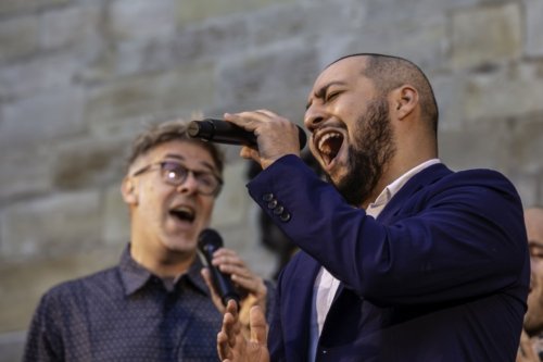 Gros plan sur Rémy du groupe Opus Jam, micro à la main en train de chanter. Dans le fond, flouté, Emmanuel l'accompagne?
