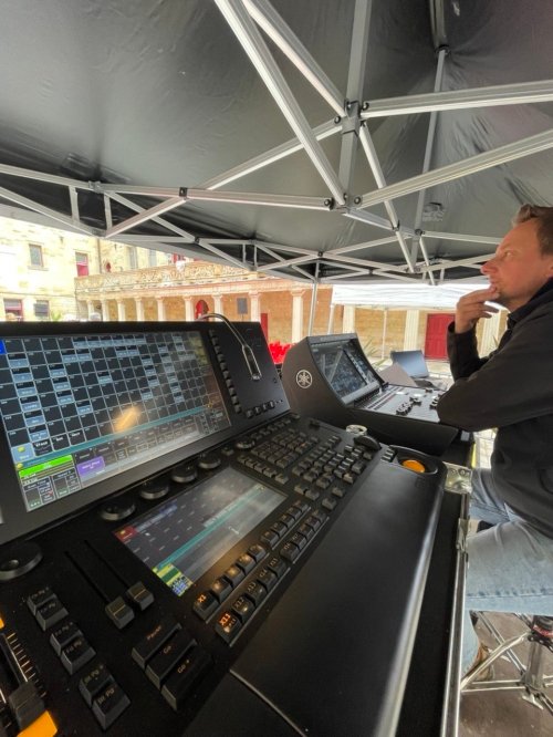 Nico, concentré devant sa console son est à l'écoute, une main sur le menton. En avant plan, une partie de la console lumière.
