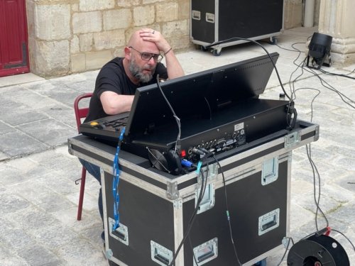 Fred, assis devant sa console lumière, une main sur la tête en pleine réflexion.
