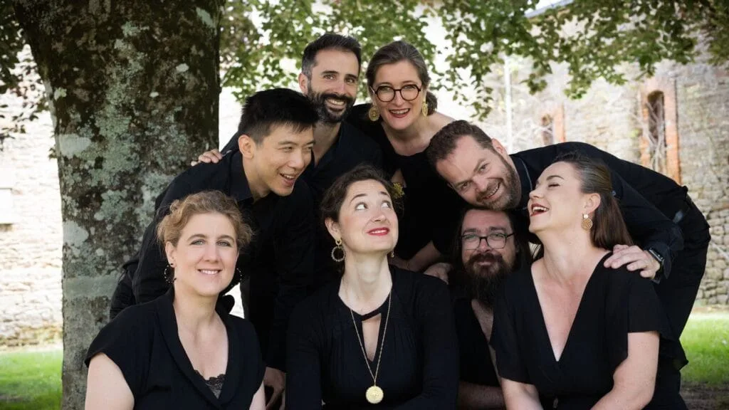 Photo du groupe Ensemble Ô regroupés et accroupis sous un arbre