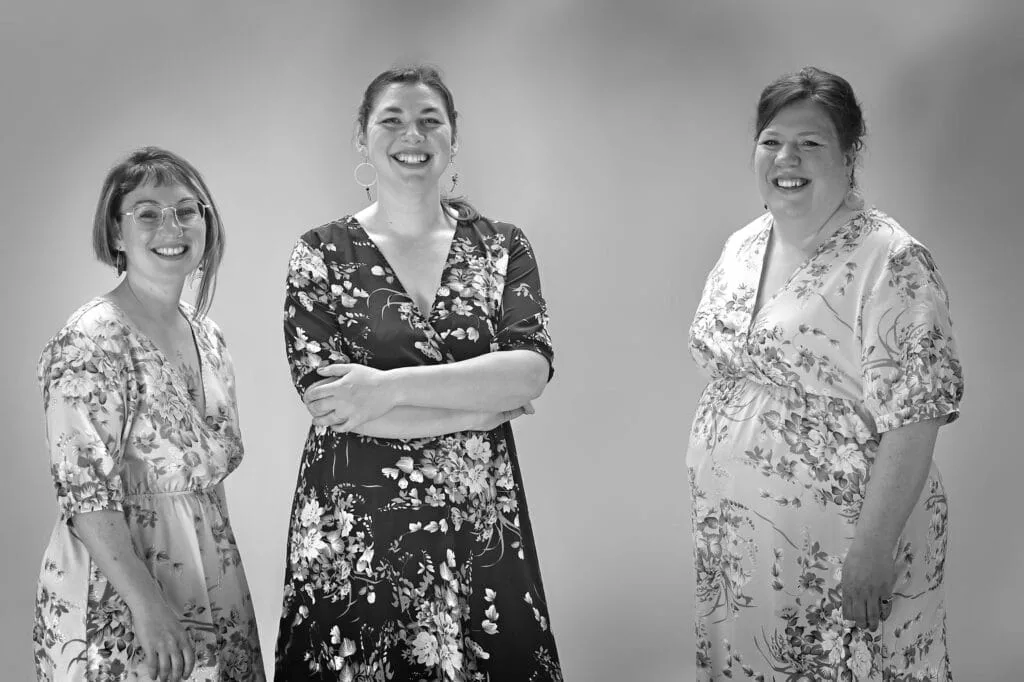 Photo, en noir et blanc, du trio Les Chanteuses Anonymes en robe fleuries