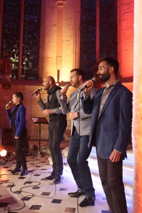 Le groupe ClimaX, micro à la main, chantent dans la nef éclairée de teintes orangées