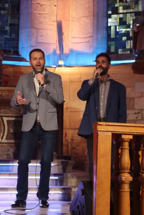 Cédric et Thibault chantent micro à la main dans la nef de l'église
