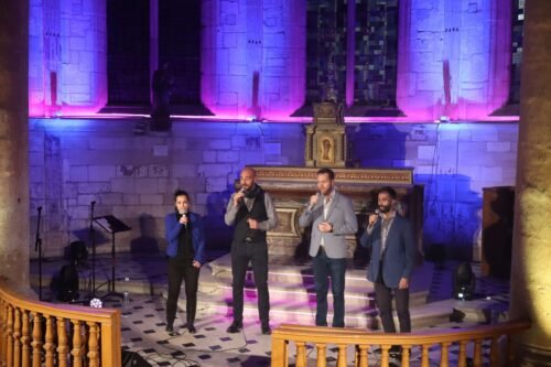 Vue en élévation du groupe ClimaX chantant dans une nef éclairée de teintes bleues et mauves