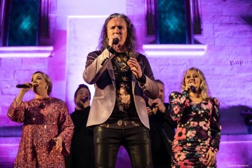 Juha, au premier plan, chante micro à la main. Les autres membres chantent en arrière plan