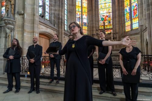 Laetitia de l'Ensemble Ô chante en écartant les bras devant les autresmembres du groupe en arrière plan
