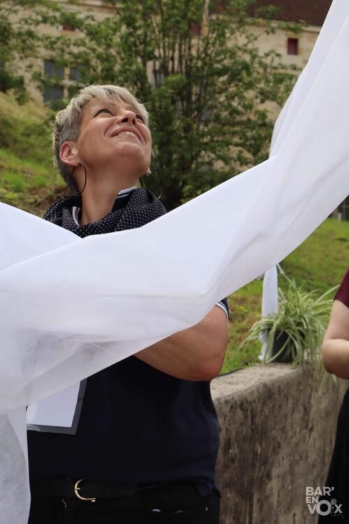 Séverine, regard vers le haut, installe la décoration sur les arceaux bien trop hauts pour elle