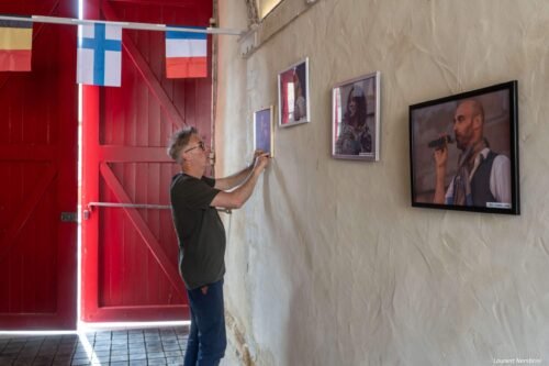 Emmanuel est en train d'accrocher des cadres dans l'entrée du collège Gilles de Trèves