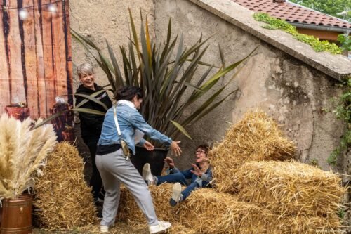 Virginie est tombée derrière une botte de paille. Nolwenn essaye de la relever sous le regard amusé de Séverine.