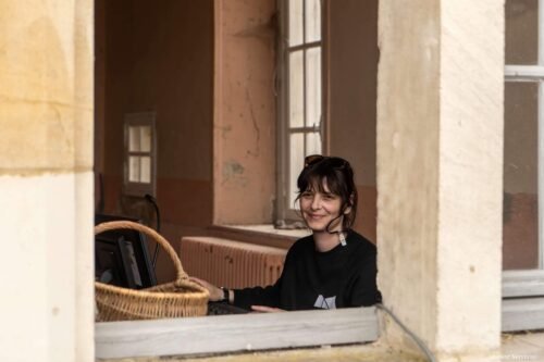Elodie, souriante derrière une fenêtre, est aux commandes de la console lumière du jardin du collège
