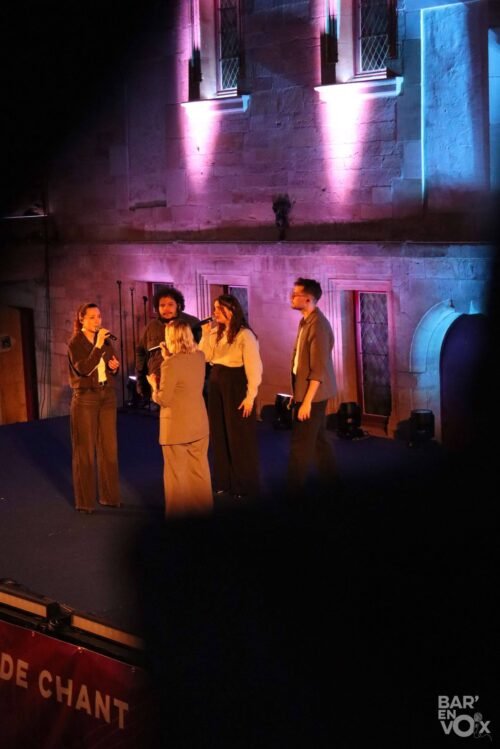 Une photo de JustVox vu des coursives devant une façade éclairée de rose et bleu