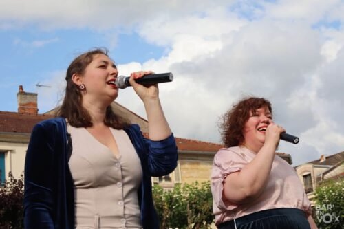 Clara et Anne, micro à la main, chantent sur la place Reggio