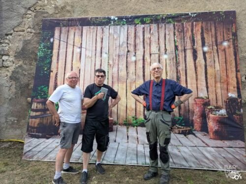 François, Sylvain (agrafeuse) à la main, et Yvon posent devant le fond du coin photo qu'ils viennent de monter