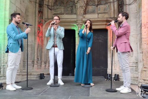 Les 4 artistes, en arc de cercle, sur scène à Longeville-en-Barrois chantent en tenant les pieds de micro