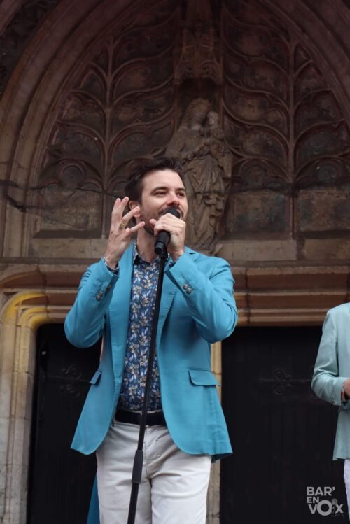 Guido, en blazer bleu, chante micro à la main