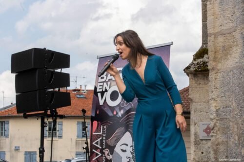 Giulia, penchée vers le public, chante en tenant le micro à la main.