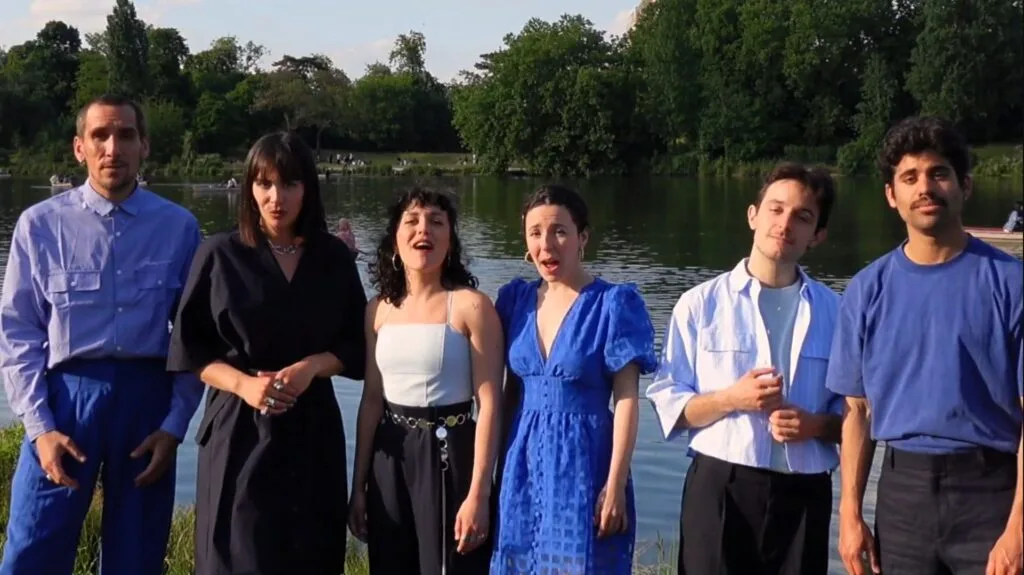 Six chanteurs devant un étang boisé