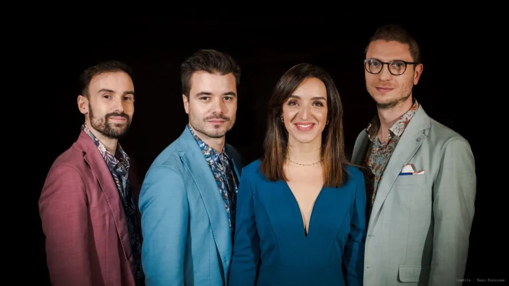 Quatre chanteurs posent devant un fond noir